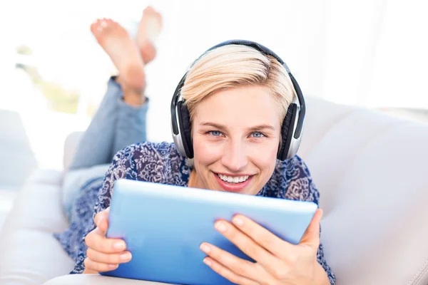 Blond kvinna på soffan lyssnar musik — Stockfoto