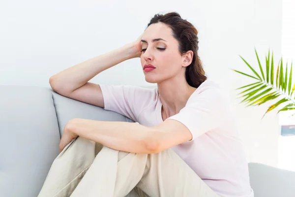 Sad brunette sitting on the couch — Stock Photo, Image