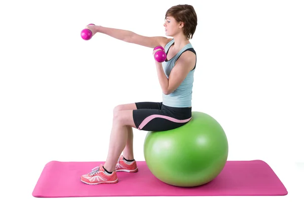 Morena exercitando com halteres na bola de fitness — Fotografia de Stock