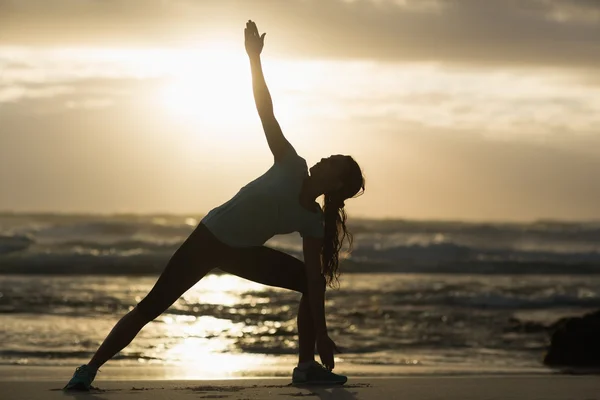 Sportig brunett stretching på stranden — Stockfoto