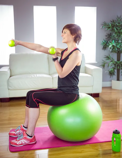 Fit mujer levantando mancuerna sentado en la bola — Foto de Stock