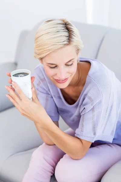 Blonde Frau auf der Couch mit einem Becher — Stockfoto