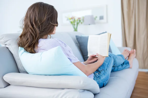 Vrouw die boek leest op de bank — Stockfoto