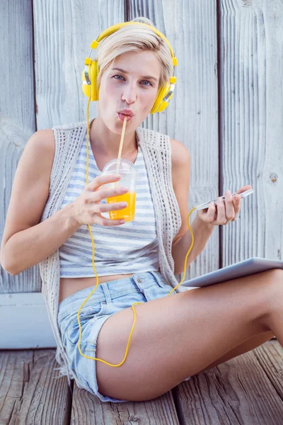 Vrouw muziek luisteren en het drinken van SAP — Stockfoto