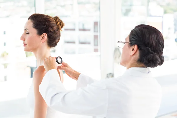 Médico examinando paciente con lupa —  Fotos de Stock