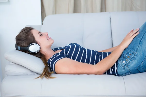Ακούγοντας μουσική όμορφη γυναίκα στον καναπέ — Φωτογραφία Αρχείου
