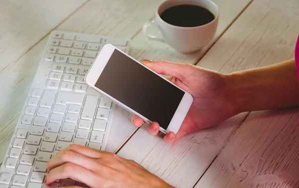 Mulher usando seu smartphone e teclado — Fotografia de Stock