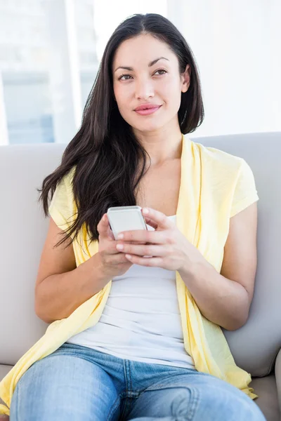 Mooie brunette gebruikend smartphone in de woonkamer — Stockfoto