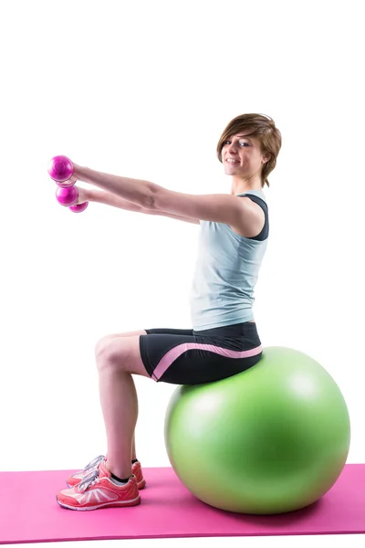 Brünette trainiert mit Kurzhanteln auf Fitnessball — Stockfoto