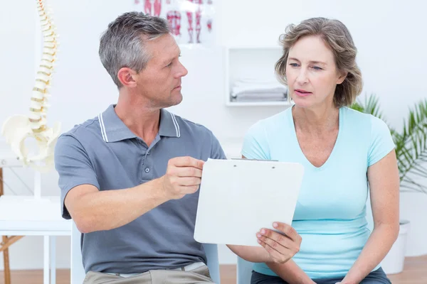 Physiotherapist showing his notes to his patient — Stock Photo, Image