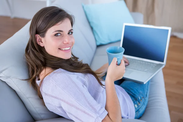 Brunette using laptop with cup of coffee — Stock Photo, Image