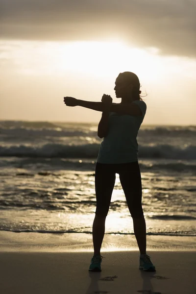 Sportowy brunetka rozciąganie na plaży — Zdjęcie stockowe