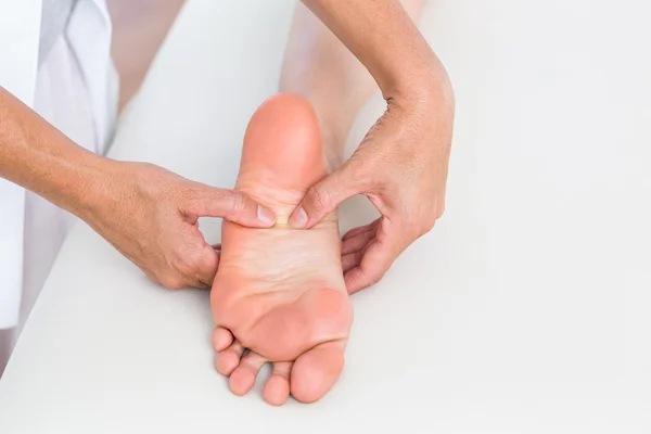 Fisioterapeuta massageando o pé de seus pacientes — Fotografia de Stock