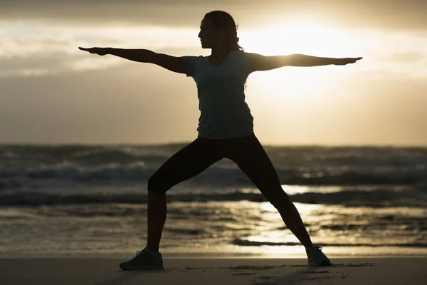 Sportig brunett stretching på stranden — Stockfoto