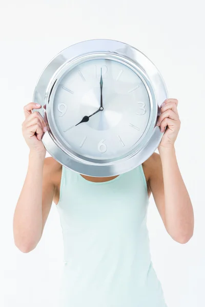 Mujer sosteniendo el reloj delante de la cabeza — Foto de Stock