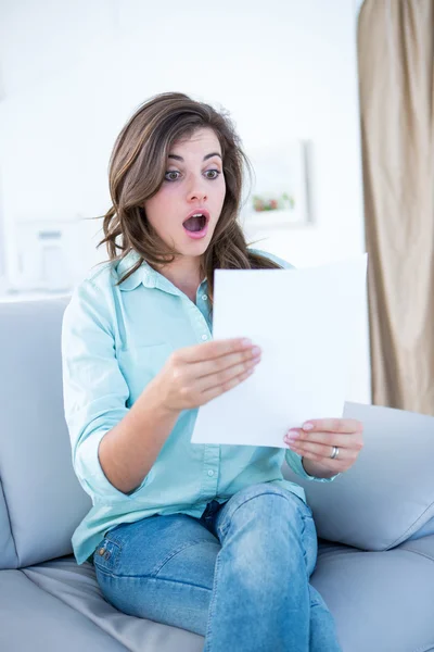 Shocked brunette looking a paper — Stock Photo, Image