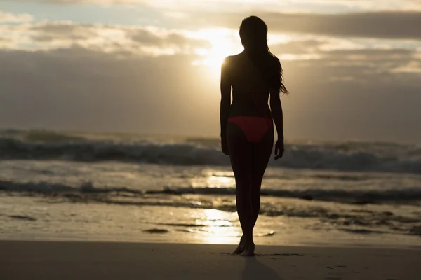 Sportig brunett promenerar på stranden — Stockfoto