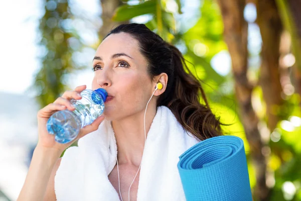 Fit schöne Brünette trinkt Wasser, während Musik hören — Stockfoto