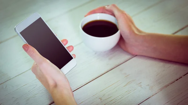 Vrouw met behulp van haar smartphone met koffie — Stockfoto