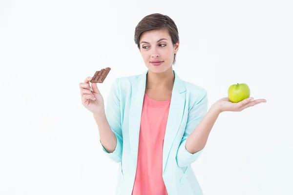 Женщина выбирает между яблоком и шоколадом — стоковое фото