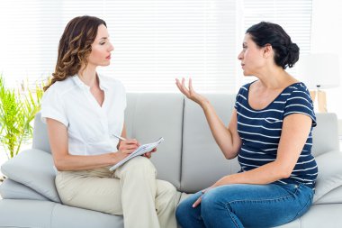 Depressed woman talking with her therapist clipart