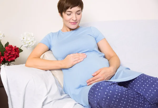 Těhotná žena uvolňující na gauči — Stock fotografie
