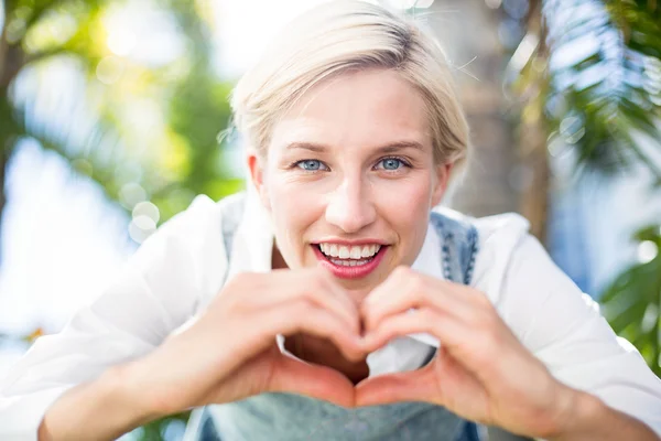 Blonda leende och gör hjärta form — Stockfoto