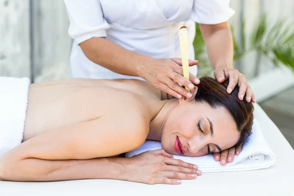 Relaxed brunette getting an ear candling treatment — Stock Photo, Image