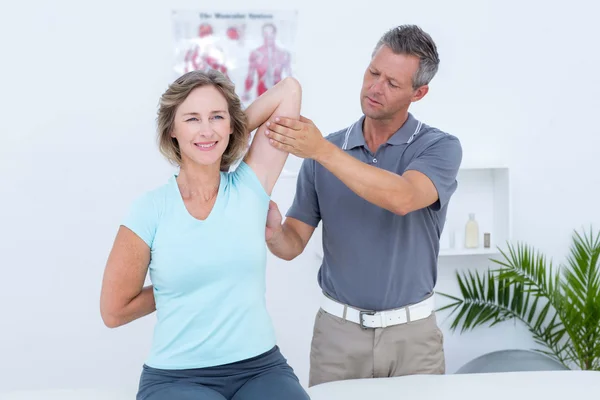 Woman stretching her arms with her doctor — Stock Photo, Image