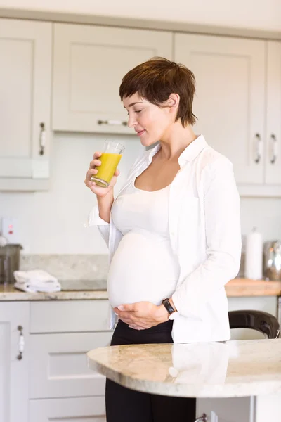 Mulher grávida tomando um copo de suco de laranja — Fotografia de Stock