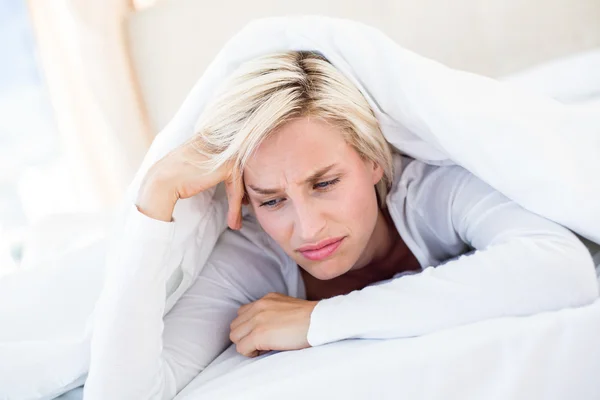 Triste donna bionda sdraiata sul letto — Foto Stock