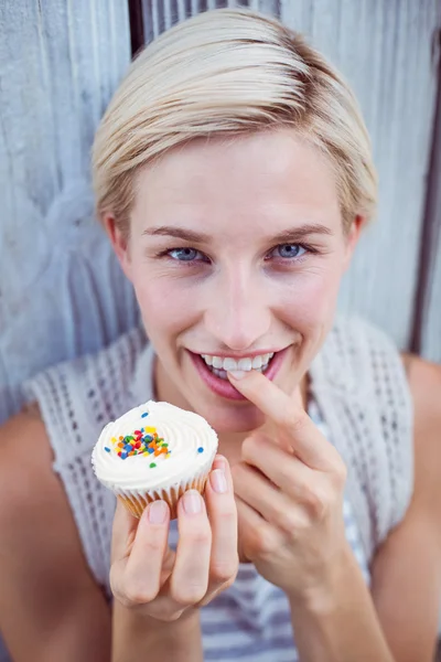 Όμορφη ξανθιά γυναίκα δοκιμάζοντας το cupcake — Φωτογραφία Αρχείου
