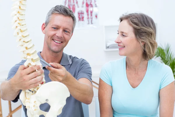 Fisioterapeuta mostrando modelo de columna vertebral a su paciente —  Fotos de Stock