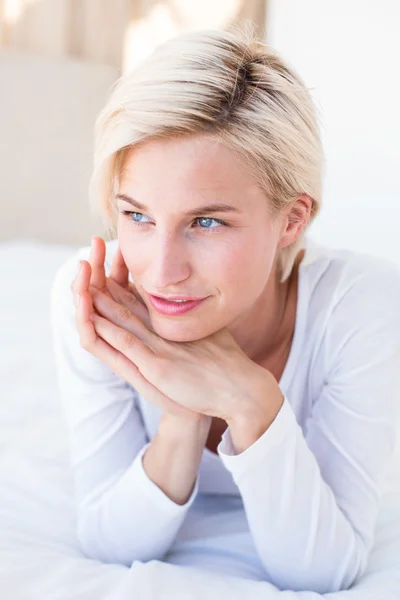 Smiling blonde woman lying on bed — Stock Photo, Image