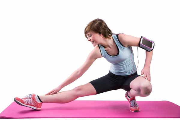Brünette streckt ihr Bein auf der Gymnastikmatte — Stockfoto