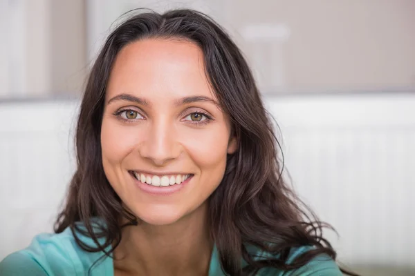 Happy brunette sitting on bed — Stock Photo, Image