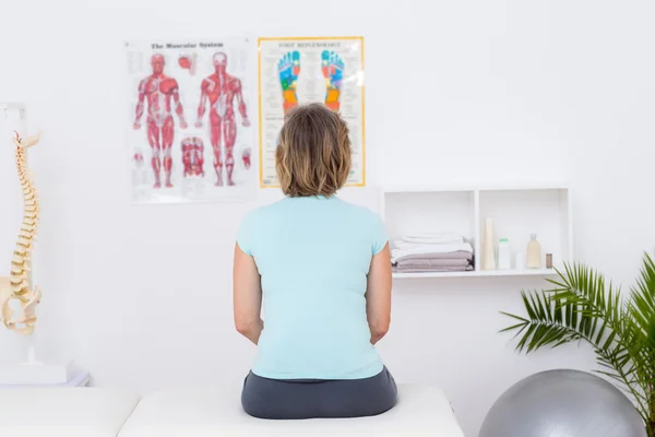 Frau sitzt auf Massagetisch — Stockfoto