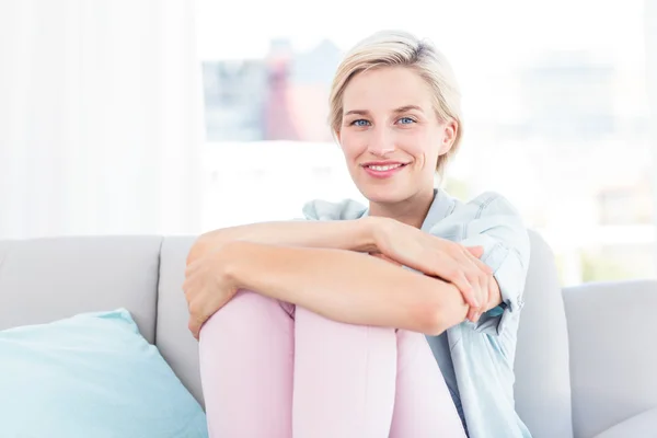 Hübsche blonde Frau sitzt auf der Couch — Stockfoto