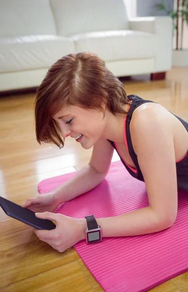 Fit vrouw die tablet pc gebruikt op mat — Stockfoto