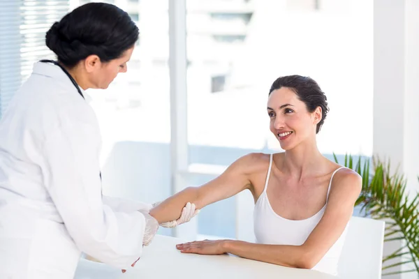 Arts kijken naar haar patiënten arm — Stockfoto