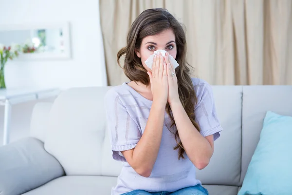 Sick woman blowing her nose looking at camera — Stock Photo, Image