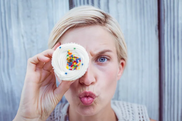 Söt blond kvinna grimaserande med cupcake — Stockfoto