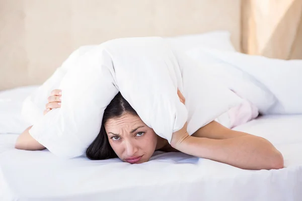 Pretty brunette hiding under the pillow — Stock Photo, Image