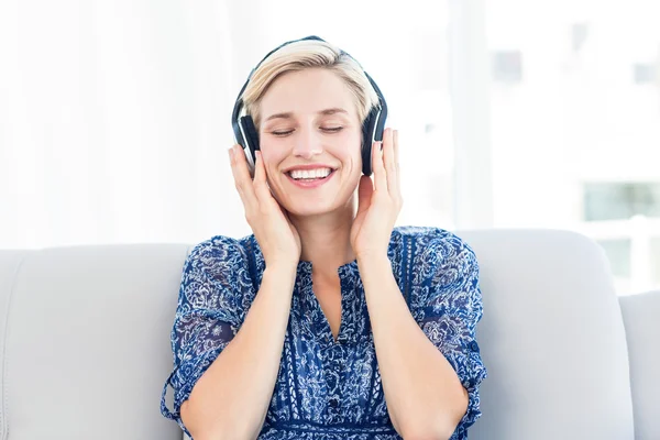 Blond kvinna lyssnar musik på soffan — Stockfoto