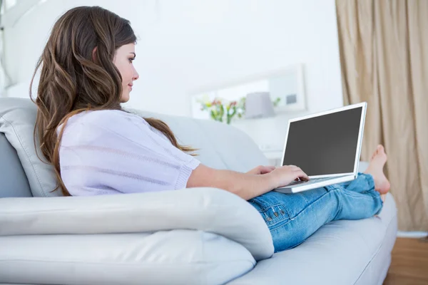 Morena bonita usando laptop no sofá — Fotografia de Stock