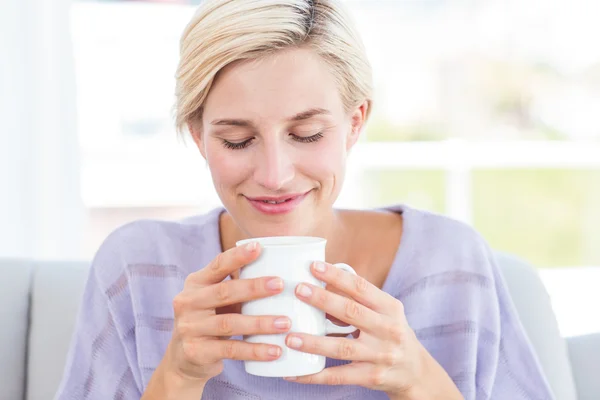 Mujer en el sofá sosteniendo una taza — Foto de Stock