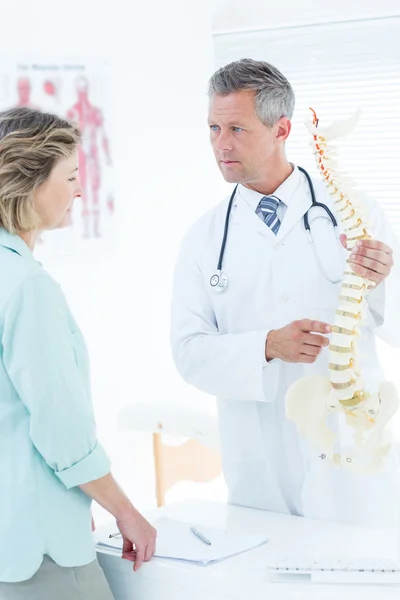 Doctor conversando con su paciente y mostrando la columna vertebral mo — Foto de Stock