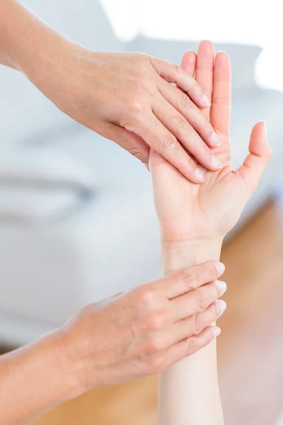 Fysiotherapeut onderzoeken haar patiënten hand — Stockfoto