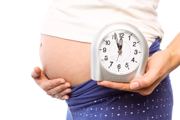 Pregnant woman showing clock and bump — Stock Photo, Image