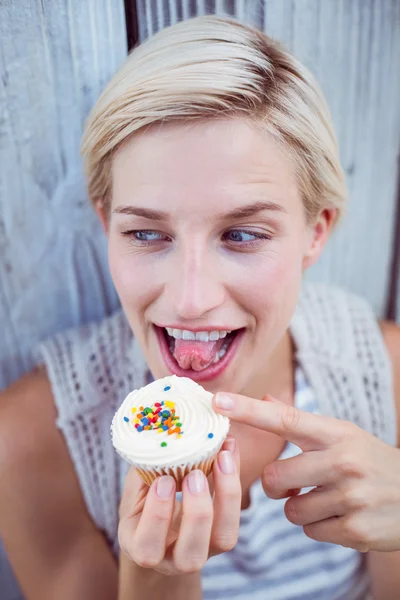 Mujer rubia bonita degustando el cupcake — Foto de Stock